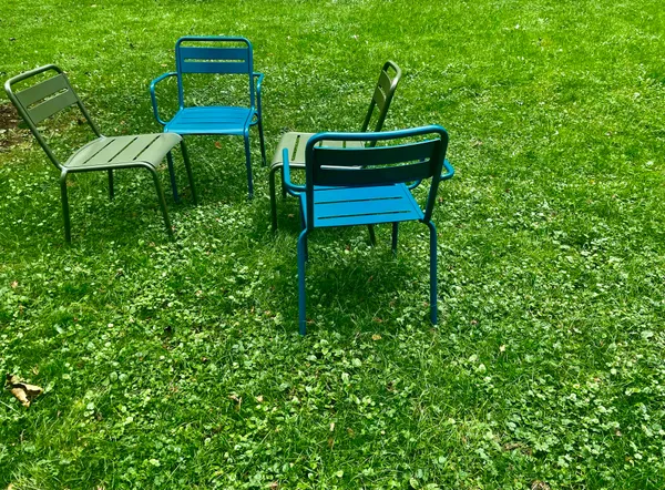 2 light blue chairs and 2 dark green chairs in a circle in the park, in Luxembourg.