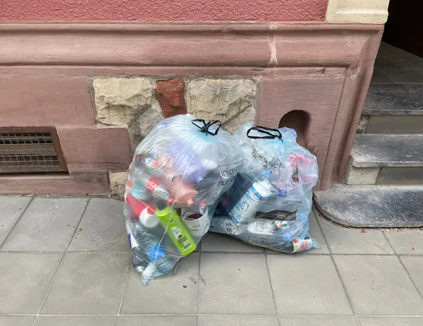 2 Valorlux sacs bleus on the pavement against a red wall, in Luxembourg.