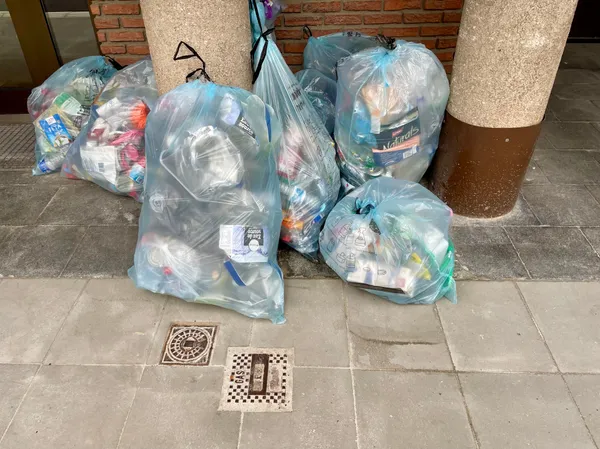 8 Valorlux sacs bleus on the pavement against 2 concrete columns, in Luxembourg.