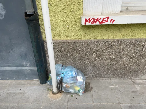 1 Valorlux sac bleu on the pavement against a yellow wall, in Luxembourg.
