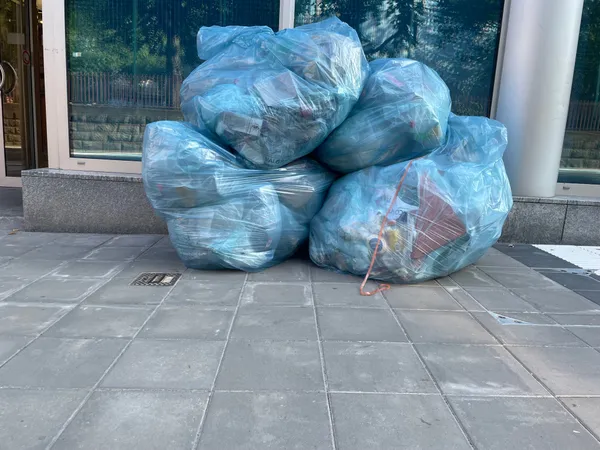 4 large Valorlux sacs bleus on the pavement against a window, in Luxembourg.