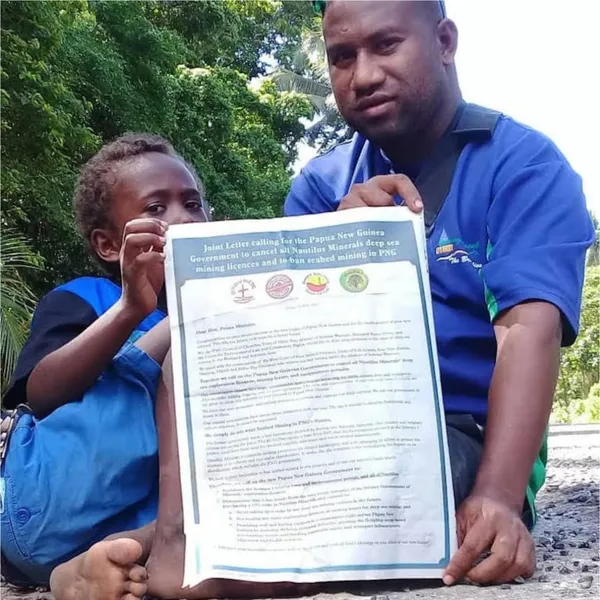 Jonathan Mesulam and his son campaigning to ban deep sea mining in PNG. Image by Jonathan Mesulam, published in MiningWatch Canada.