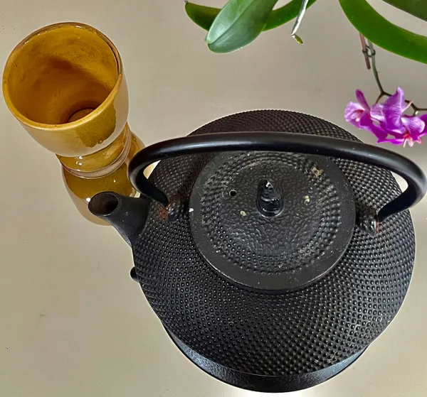 Black cast-iron teapot and ochre cup.