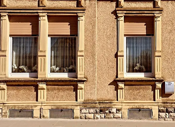 3 windows of a yellow house in Luxembourg.